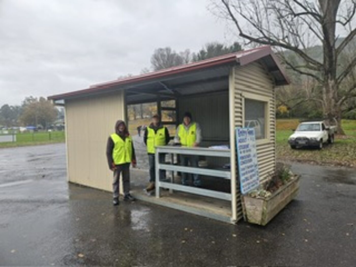 BUMS gate crew in hi-vis at the Bright footy ground gate booth on a wet day